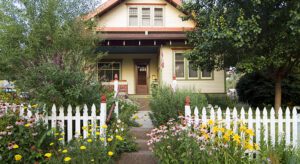 A house with flowers growing around it and a white picket fence.