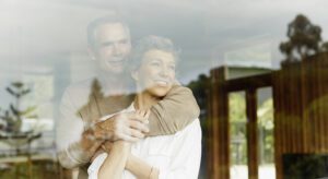 A man and woman hugging in front of a window.