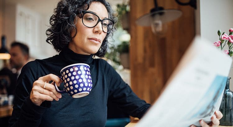 A woman sitting at a table with a cup of coffee.