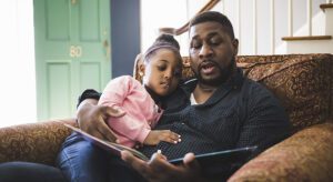 A man and his daughter are reading together.