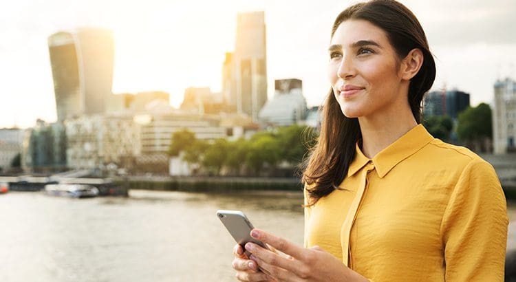 A woman in yellow shirt holding a cell phone.