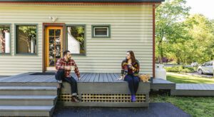 Two people sitting on a porch with one of them talking.