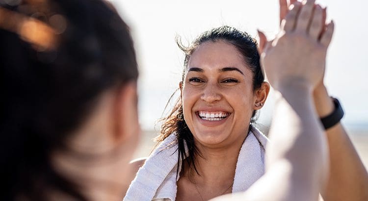 A woman smiling while standing next to another person.