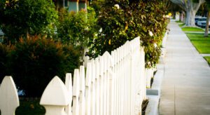 A white picket fence with trees in the background.