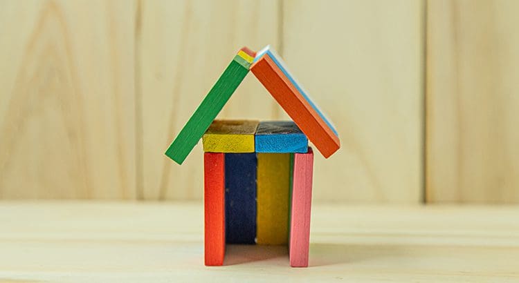 A colorful wooden toy house with a roof.
