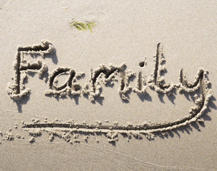 A family written in the sand on the beach.