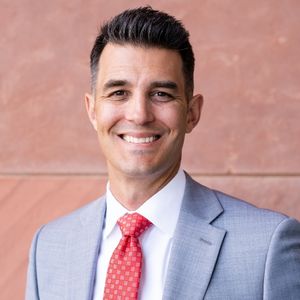 A man in a suit and tie smiling for the camera.