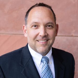 A man in suit and tie smiling for the camera.