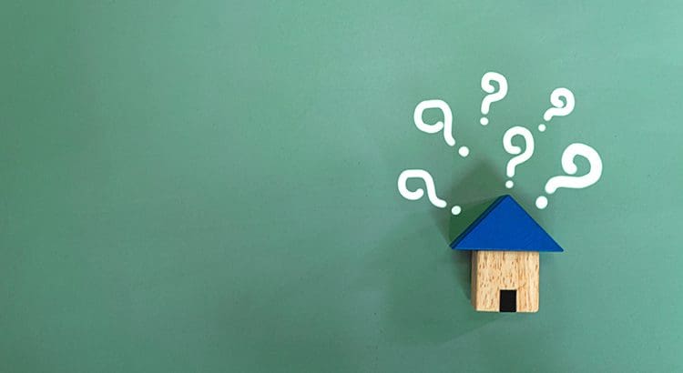 A wooden house with question marks coming out of it.