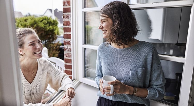 A woman holding a coffee cup talking to another person.