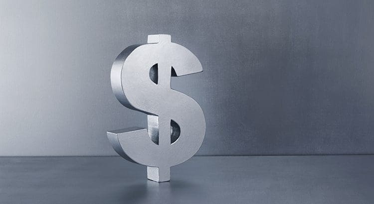A silver dollar sign sitting on top of a table.