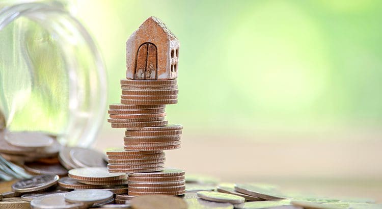 A stack of coins with a house on top.