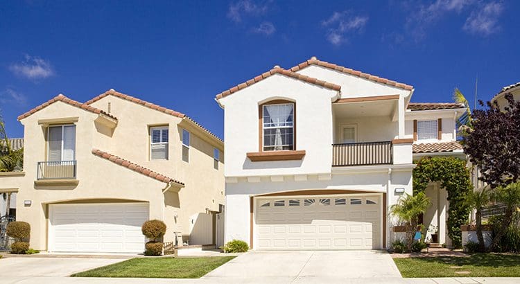 A white house with two garage doors and a driveway.