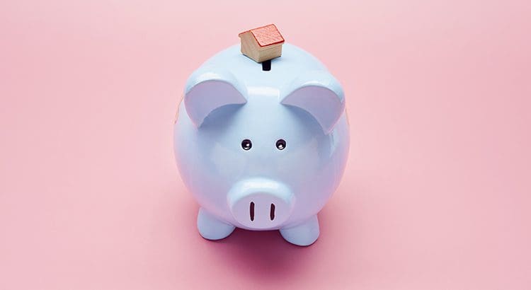 A piggy bank with a small house on top of it.