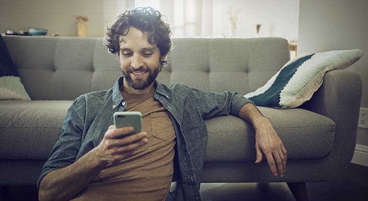 A man sitting on the couch looking at his phone.