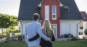 A man and woman standing in front of a house.