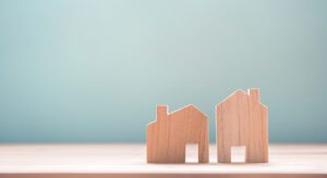 A wooden model of two houses on top of a table.