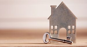 A key sitting next to a house on top of a table.