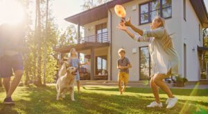 A man and his family playing frisbee with their dog.