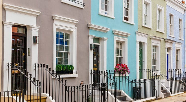 A row of houses with iron railings and flowers.