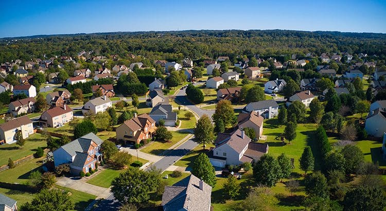A view of houses from above, with trees in the background.