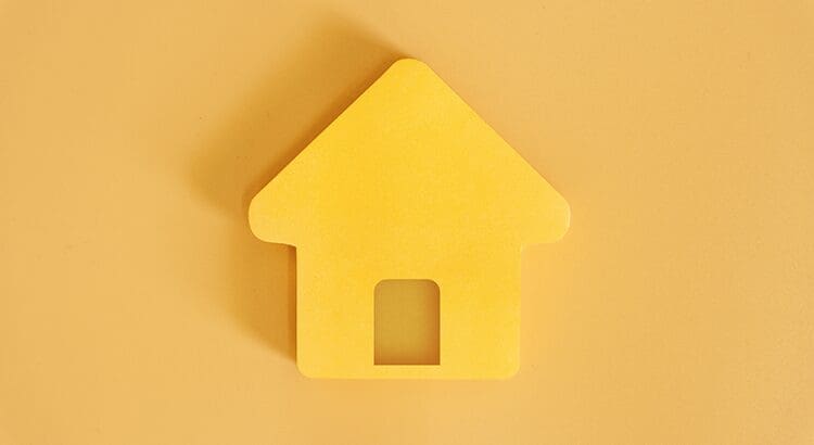 A yellow house shaped object on top of a wall.