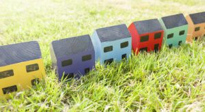 Three toy houses in a row on the grass.