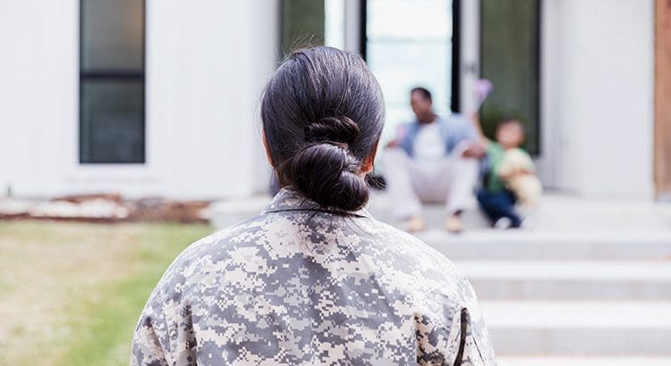 A woman in military fatigues is sitting on steps.