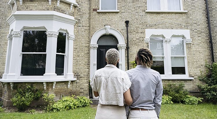 Two people standing in front of a house.