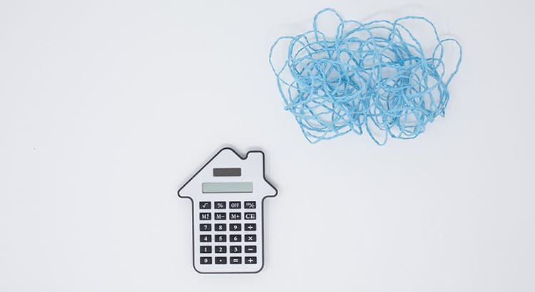 A house shaped calculator sitting next to some blue yarn.
