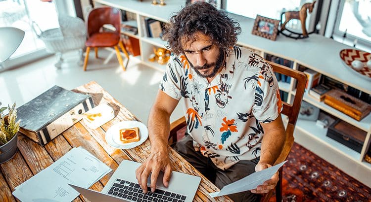 A man sitting at a table with papers and a laptop.