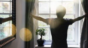 A person standing in front of a window with their arms outstretched.