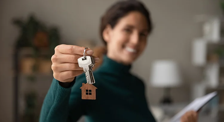A woman holding out keys to her new home.