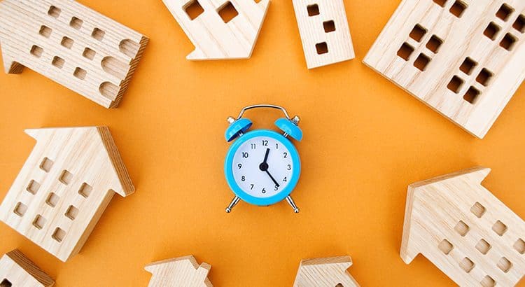A blue alarm clock surrounded by wooden blocks.