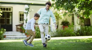 A man and boy playing soccer in the yard.