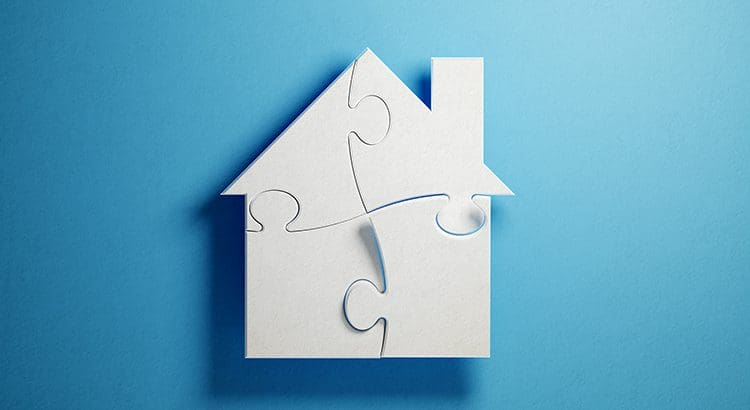 A white puzzle piece house on top of blue background.
