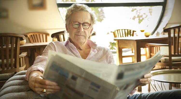 A man sitting down reading the paper.
