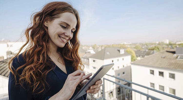 A woman is holding her tablet and smiling.