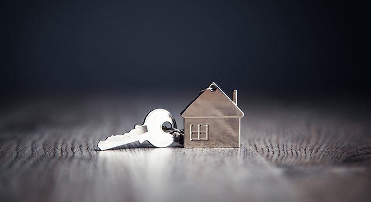 A key is in front of a small house.