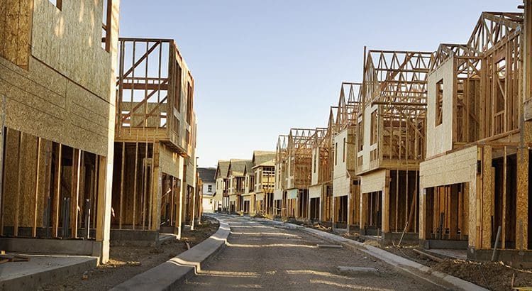 A row of houses under construction on the side of a street.