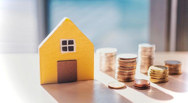 A yellow house sitting on top of some coins.