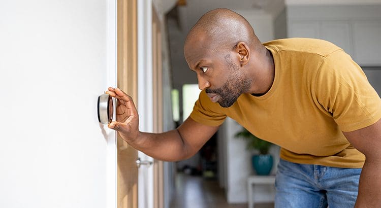 A man is looking at the temperature on an outside thermometer.