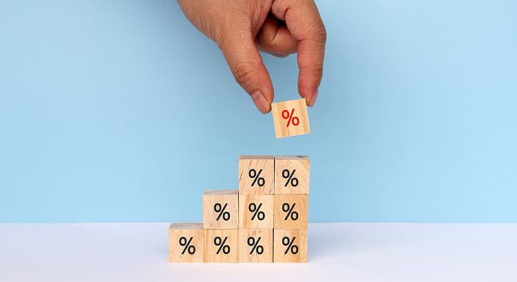 A hand holding a cube with percentages on it.