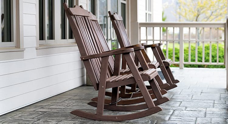 Two brown rocking chairs are on a porch.