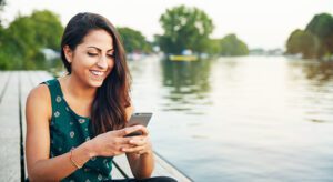 A woman sitting on the side of a boat looking at her phone.