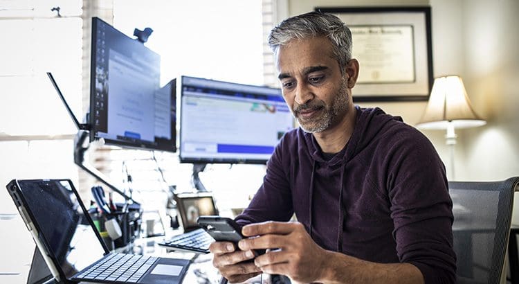 A man sitting at his desk looking at his phone.