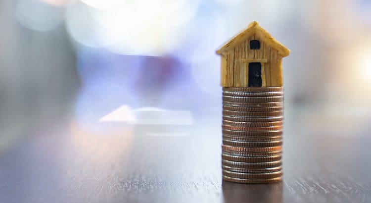 A stack of coins with a small house on top.