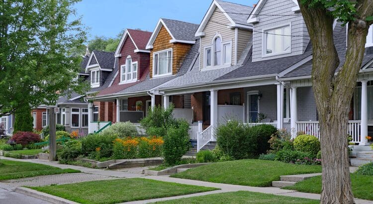 A row of houses with green grass on the front lawn.