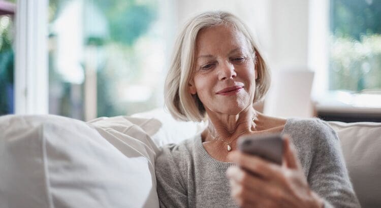 A woman sitting on the couch looking at her phone.