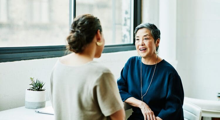 Two women are talking to each other in a room.